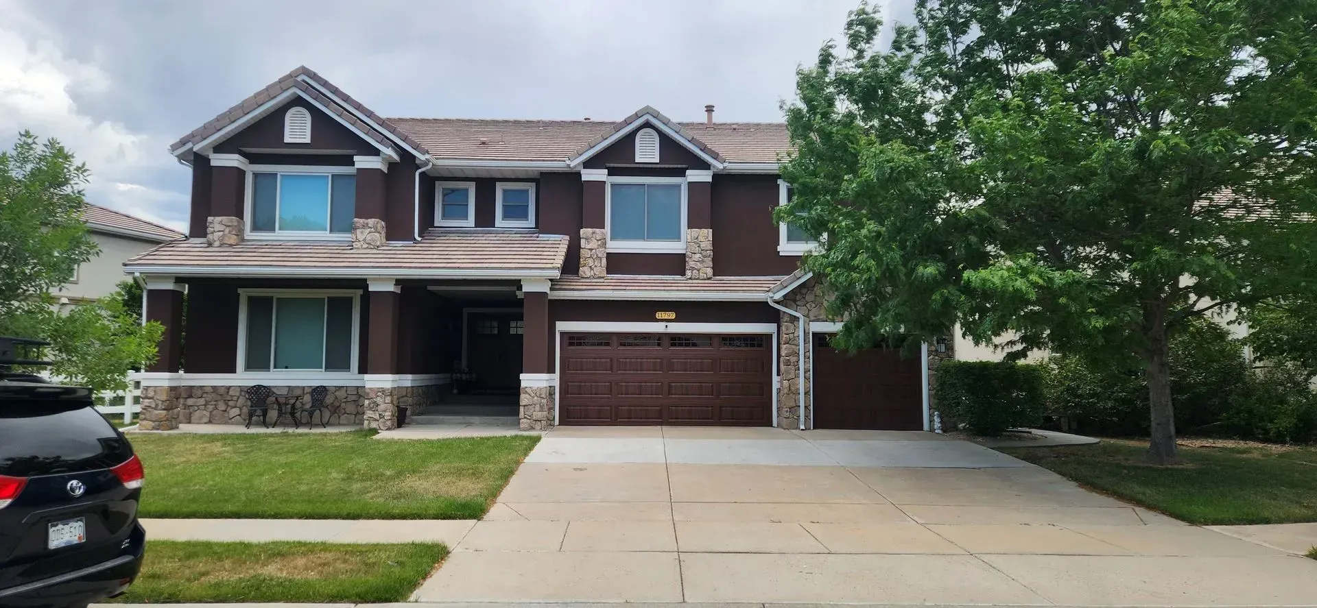 A large brown house with a car parked in front of it.