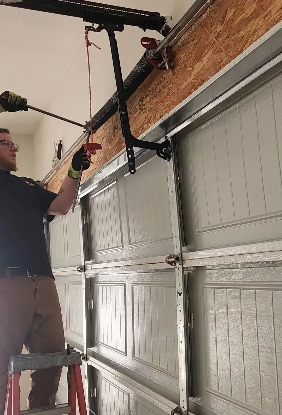 A man is working on a garage door with a drill.