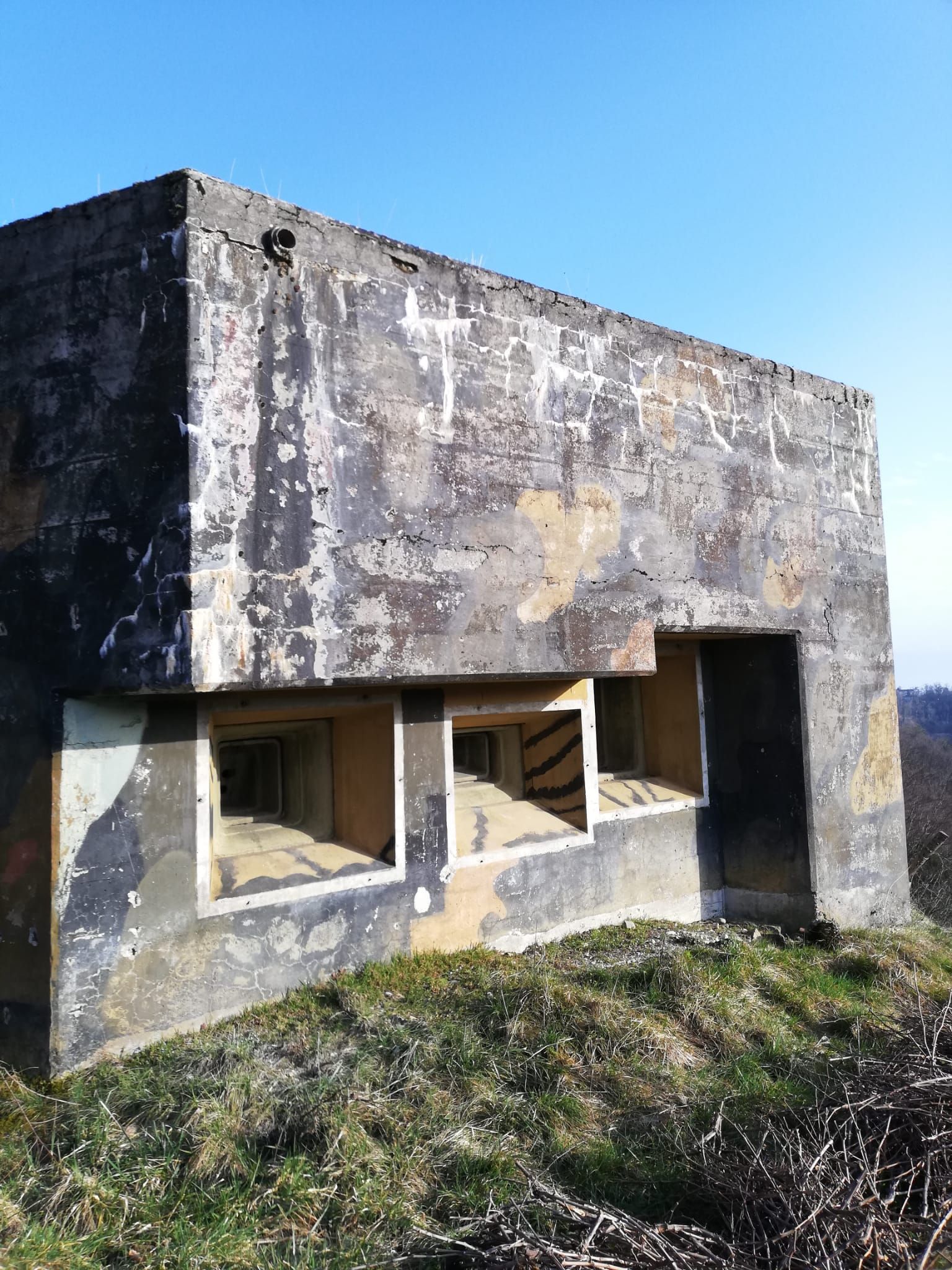 Un bunker se dresse au sommet d’une colline herbeuse.