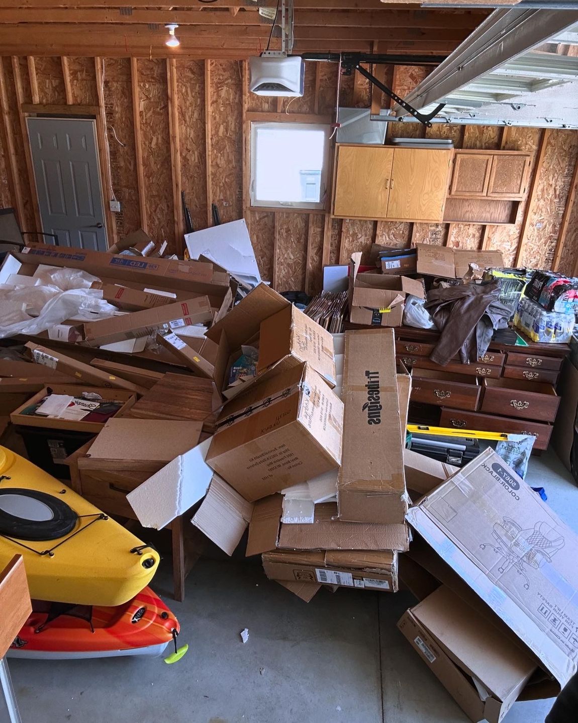 A garage filled with lots of boxes and a kayak.