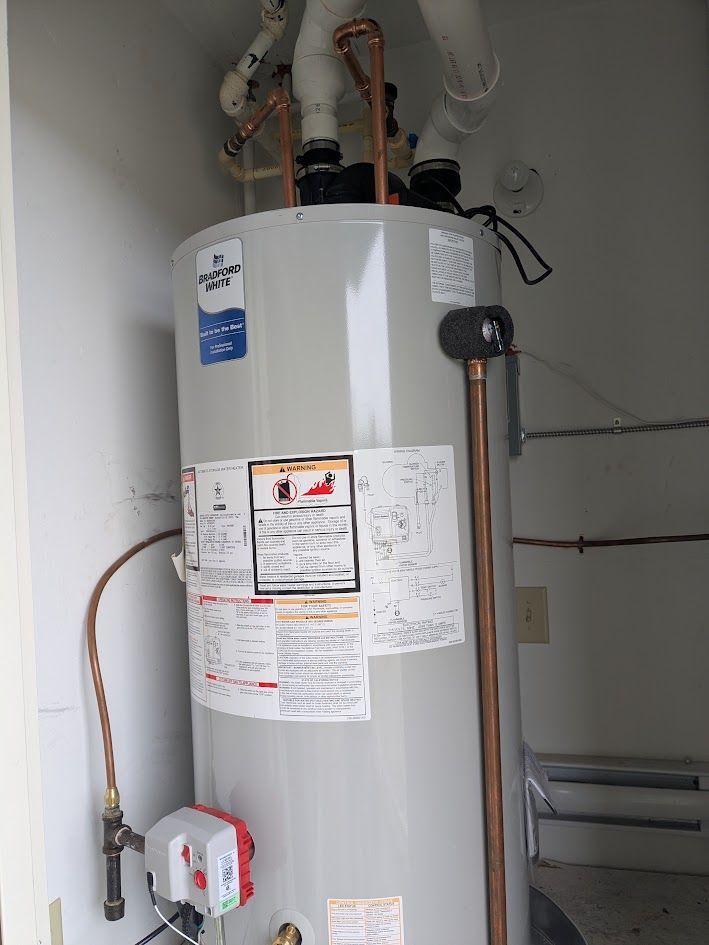 Tall gray water heater with pipes and labels in a utility room