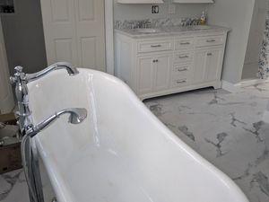 Bathroom under renovation with exposed floor, tools, and a toilet against white tiled walls
