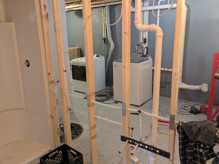 Unfinished basement with exposed wood framing, HVAC units, and plumbing pipes.