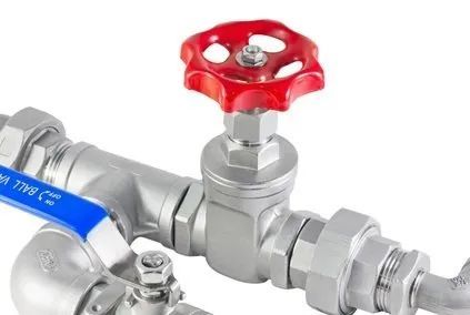 A close up of a stainless steel valve with a red handle