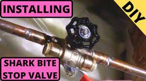 A shark bite stop valve is being installed on a copper pipe.