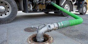 A truck is pumping water into a manhole cover.