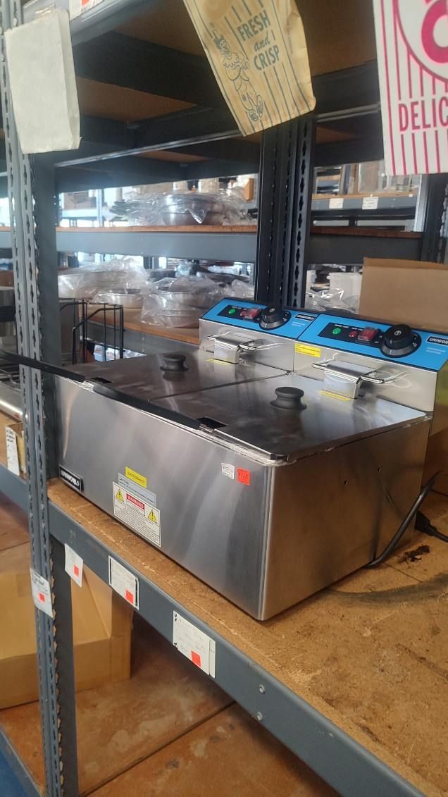 A fryer is sitting on top of a wooden shelf in a warehouse.