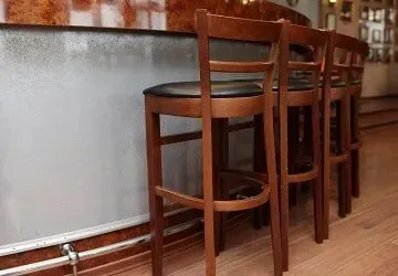 A row of wooden bar stools sitting next to a bar in a restaurant.