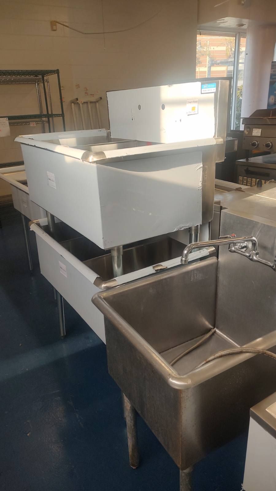 A row of stainless steel sinks in a kitchen.