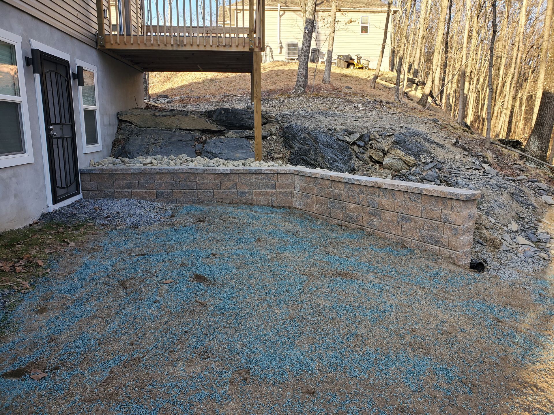 A house with a deck and a brick wall in front of it.