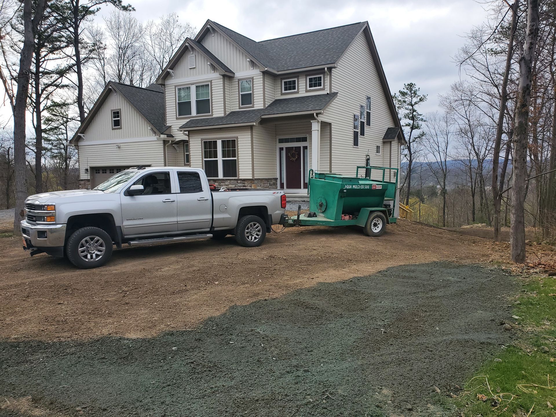 A white truck is parked in front of a large house with a trailer attached to it.