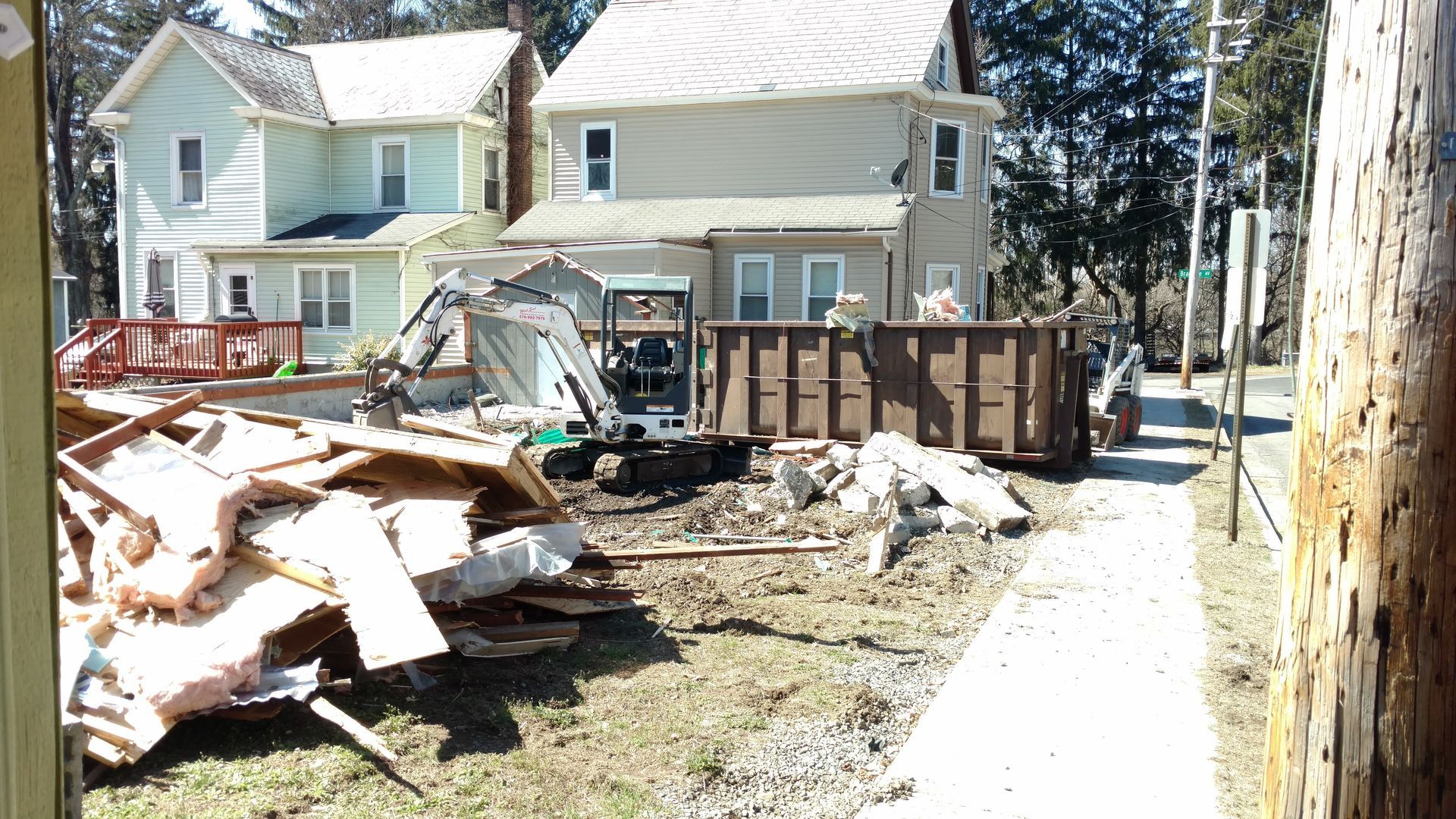 A pile of wood is sitting in front of a house that is being demolished.