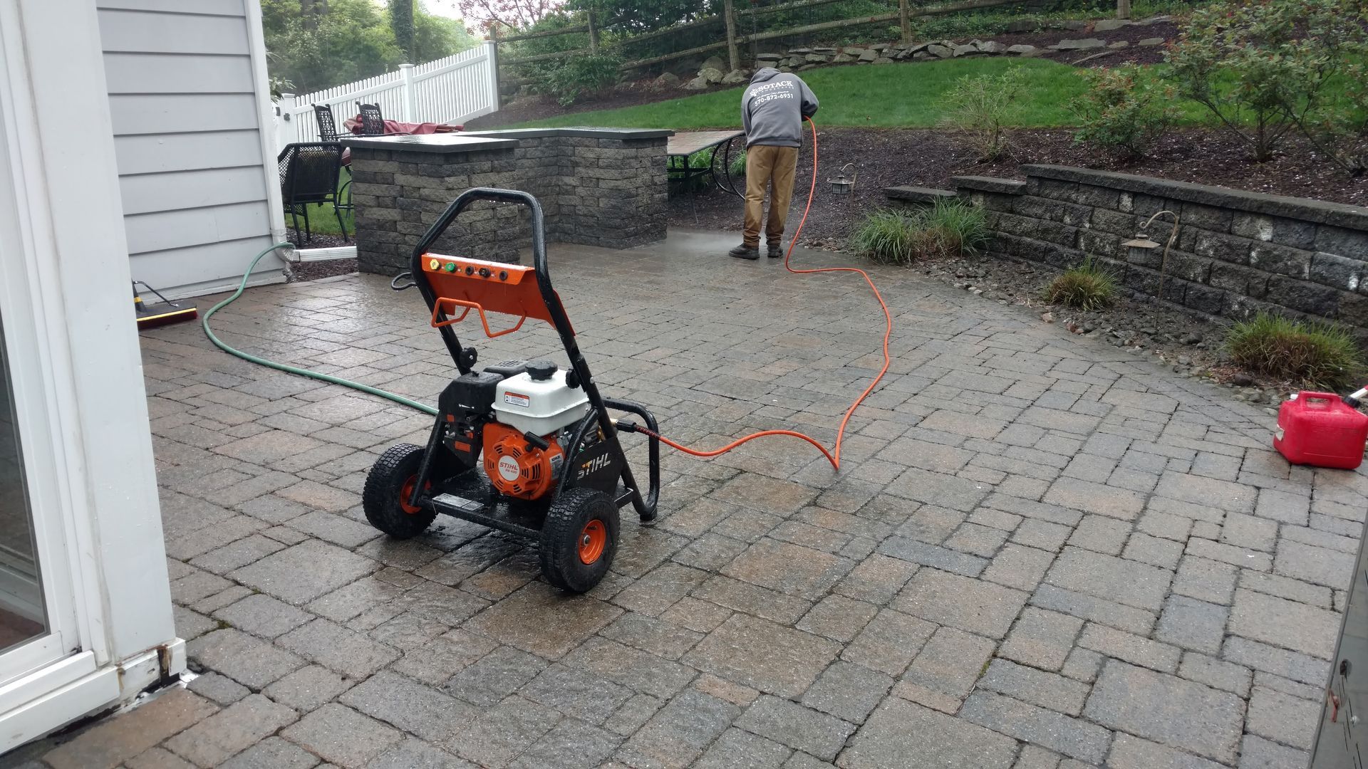 A man is cleaning a patio with a pressure washer.