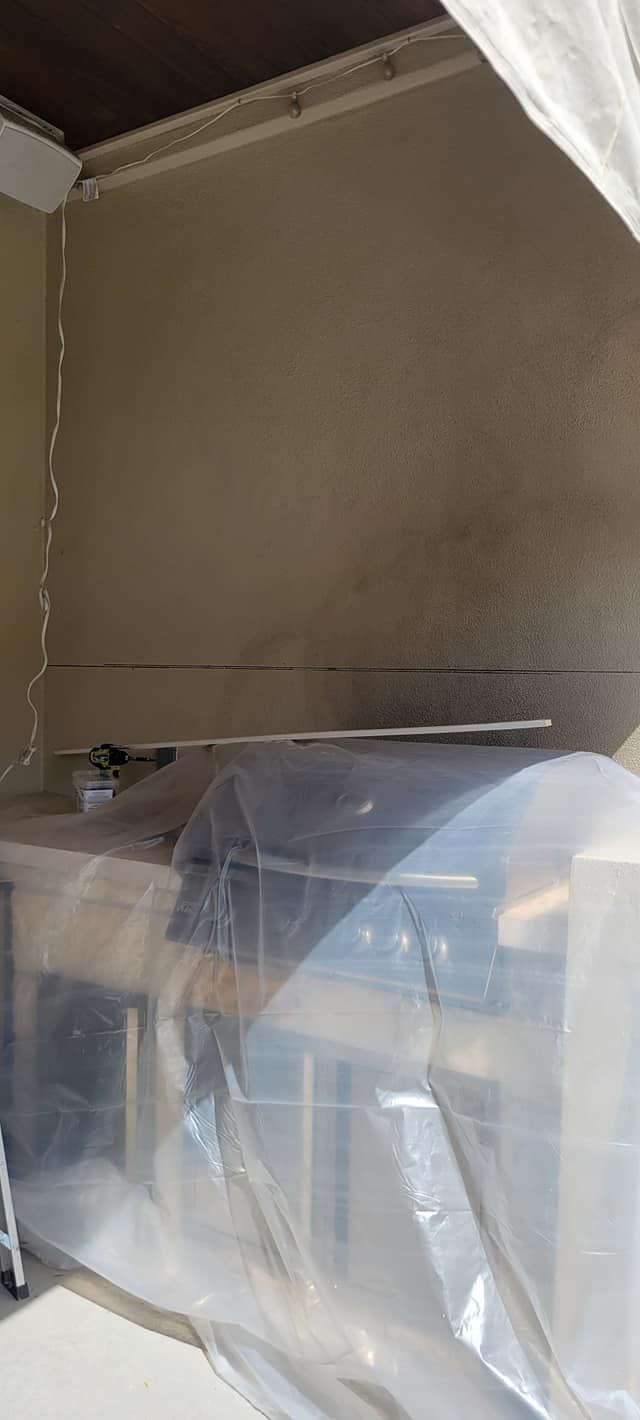 A room with a covered stainless steel appliance. The walls are beige, and the ceiling is dark brown. 