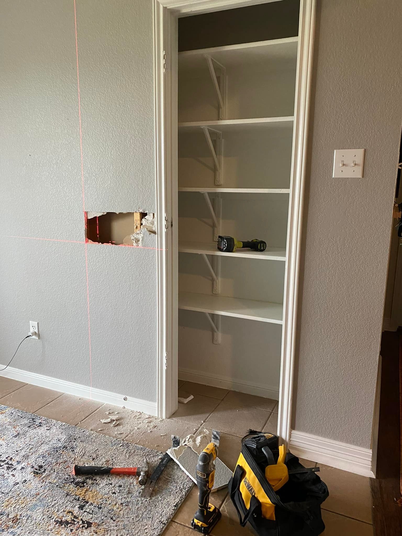 Closet renovation in progress: shelves installed, electrical work visible, tools on floor. 