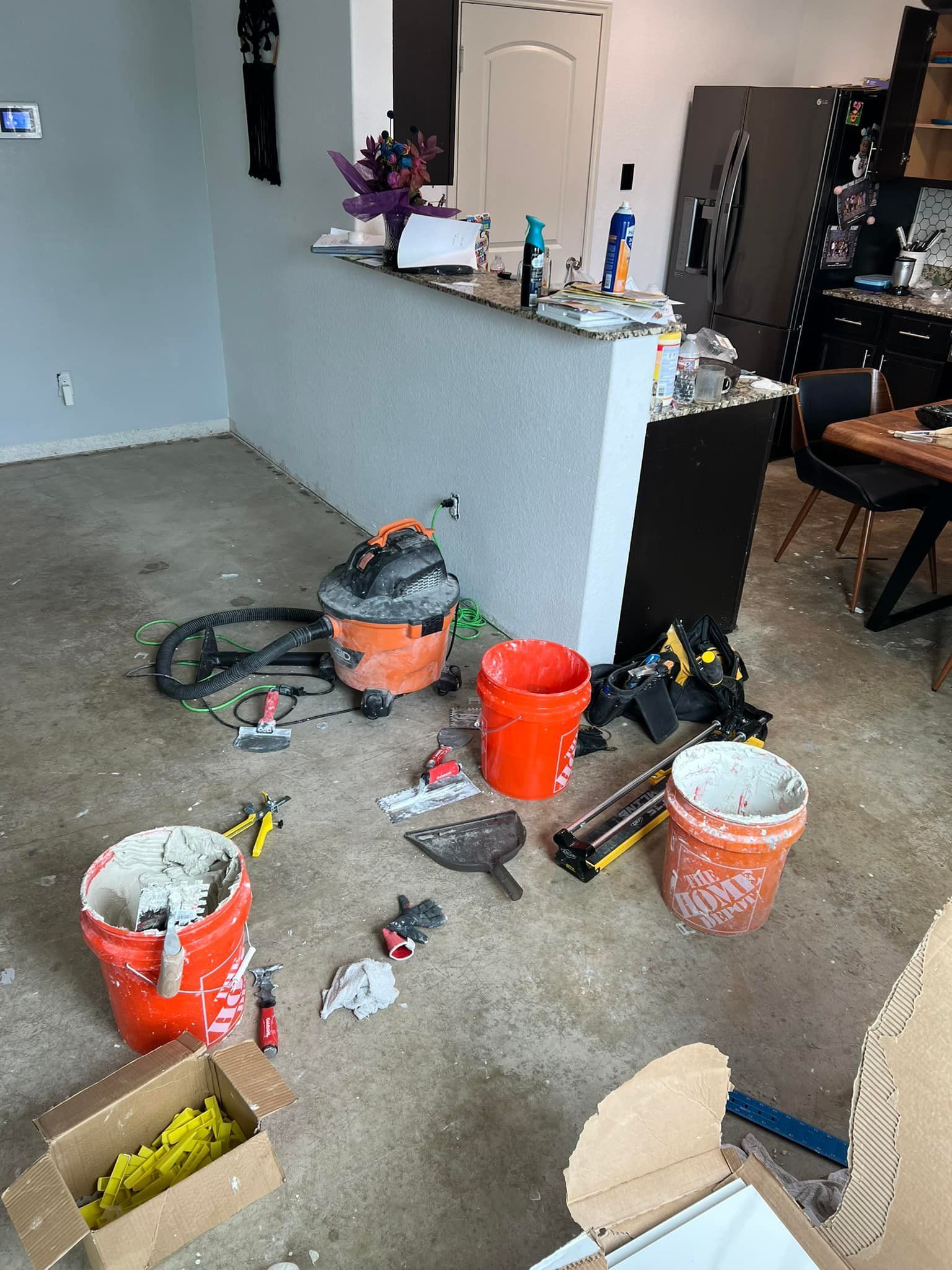 A room under renovation with tools, buckets, and debris scattered on the floor.
