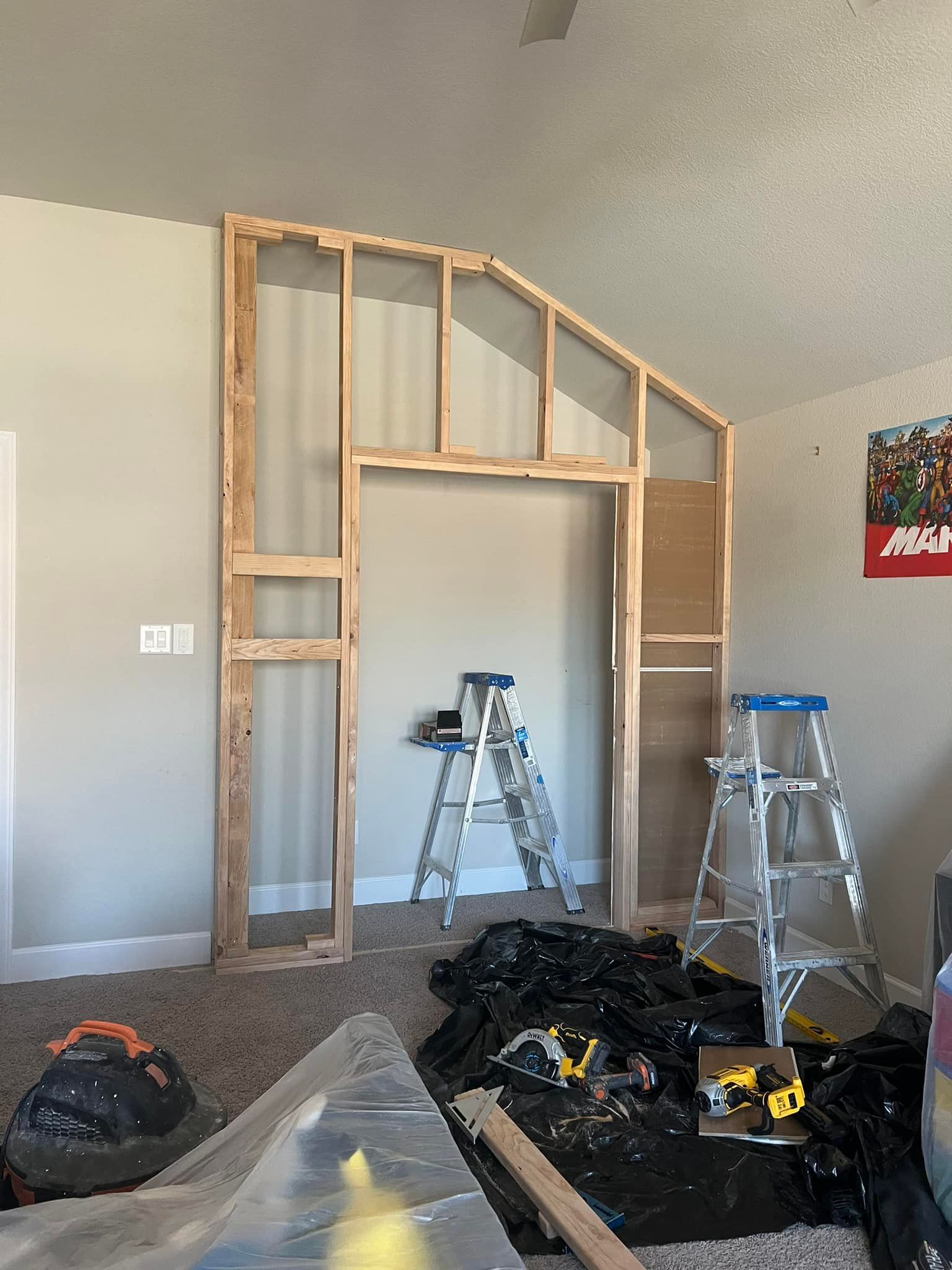 Interior room construction with a wooden frame. Ladders and tools on the floor, suggesting ongoing carpentry work.