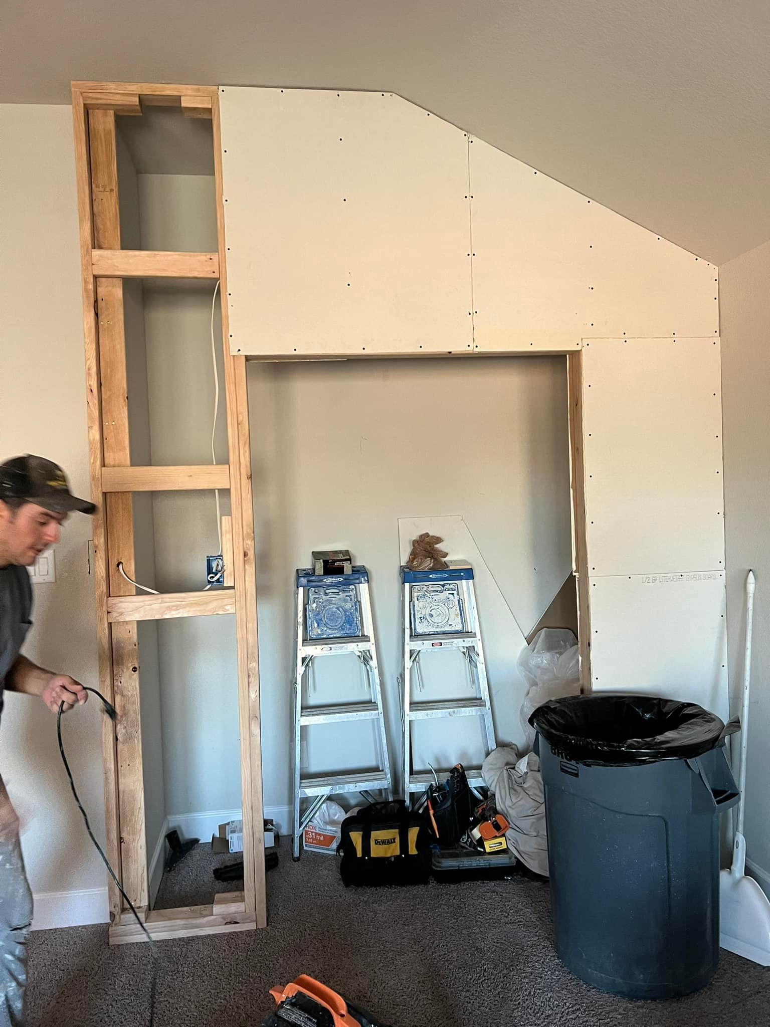 Construction in progress: Man installing electrical wiring near a wooden frame