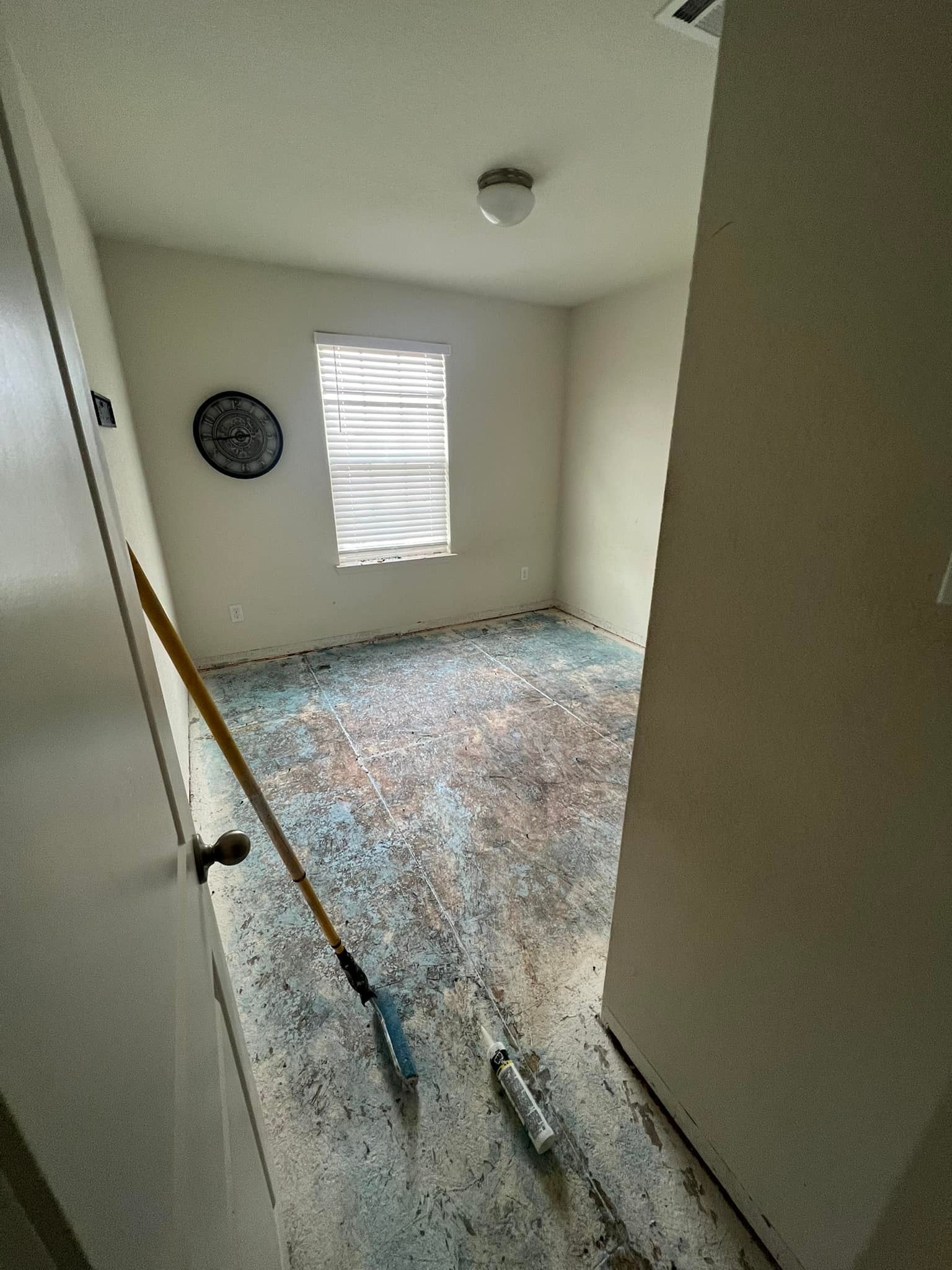 View from doorway into a small room with a patterned carpet. A broom rests on the floor.