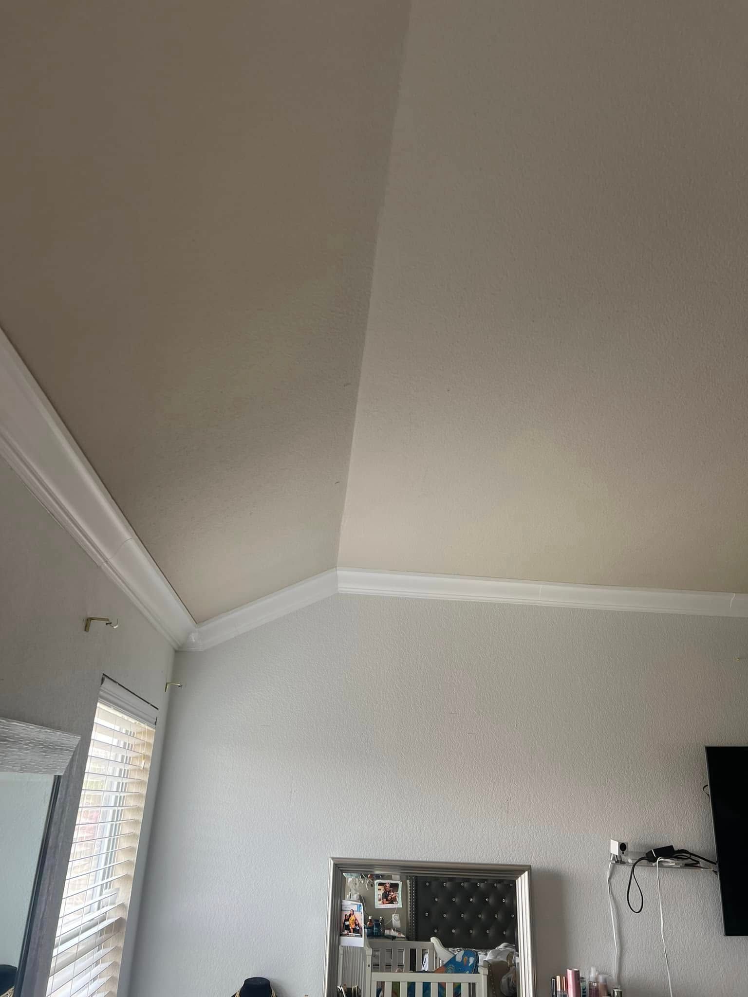 A room with a textured, light-colored wall and ceiling, with crown molding along the edges.