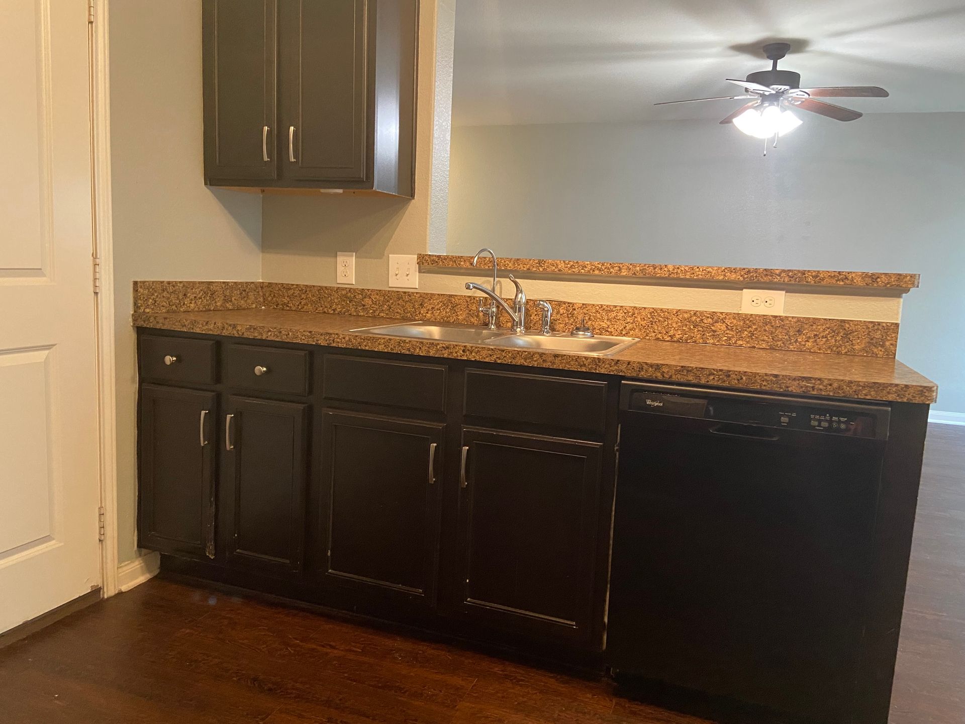 Kitchen with dark brown cabinets, speckled countertops, and a stainless steel sink. 