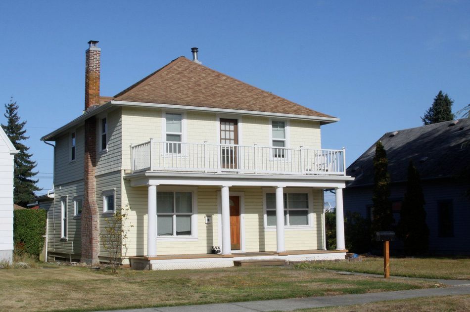 A beige retractable awning extended from a white-sided house with black trim.