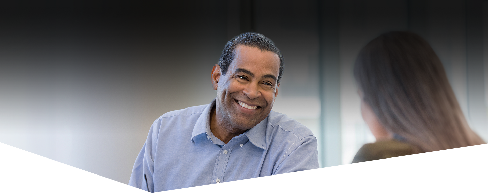 A man in a blue shirt is smiling while talking to a woman.