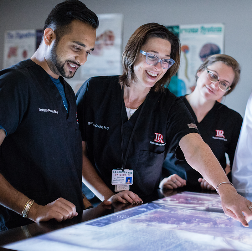 A group of people wearing scrubs looking at x rays.