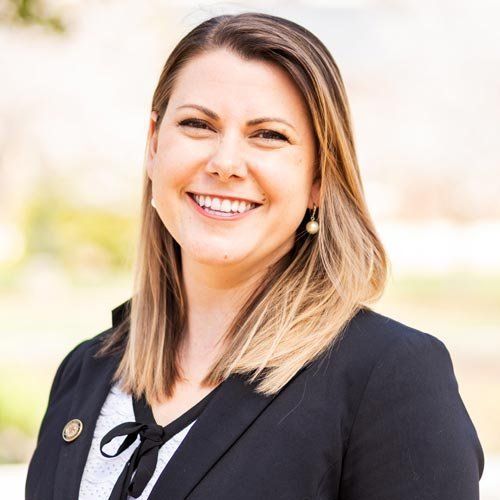 A woman in a black jacket is smiling for the camera.