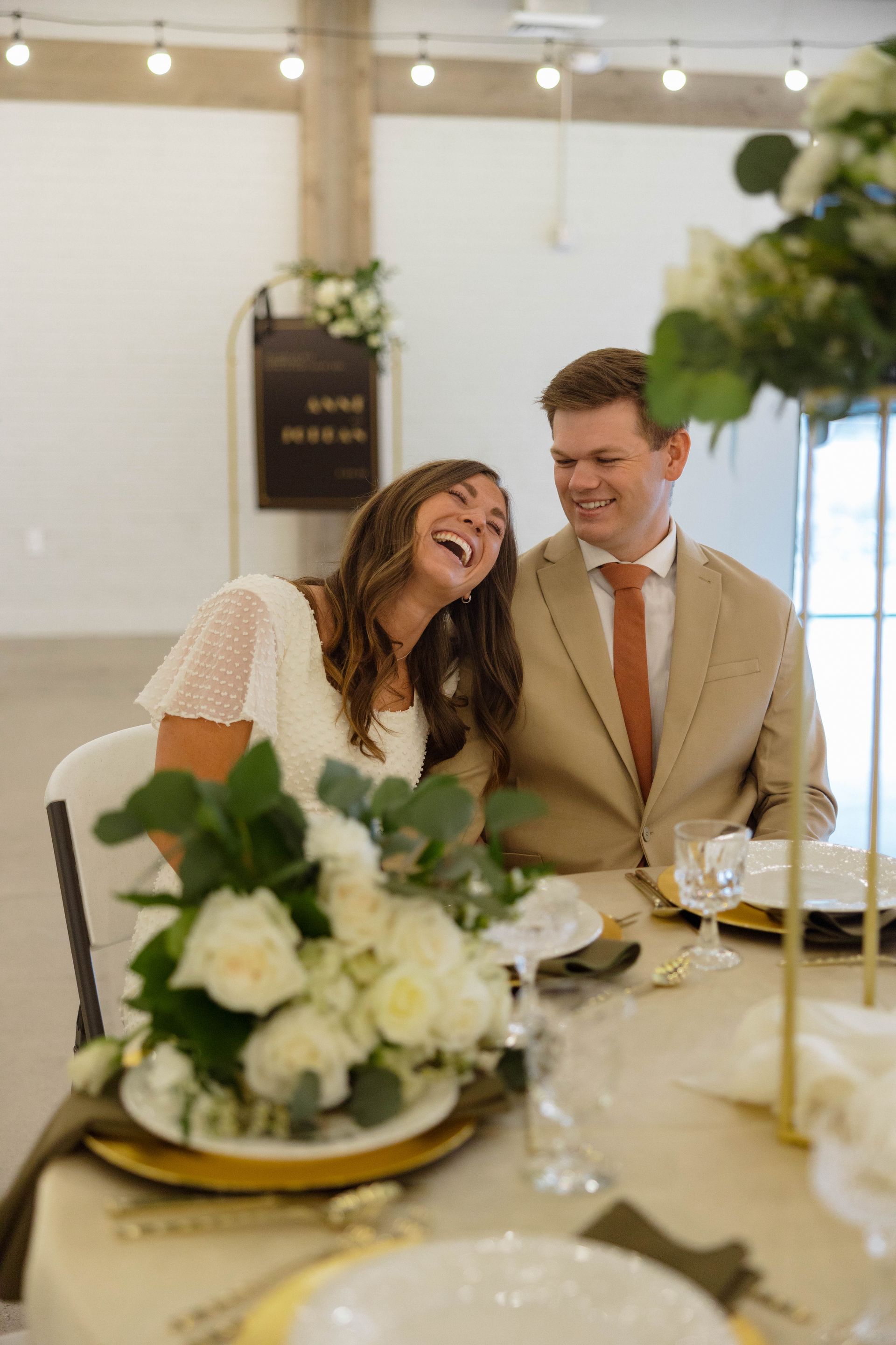 Two women are holding a wedding dress in a room.
