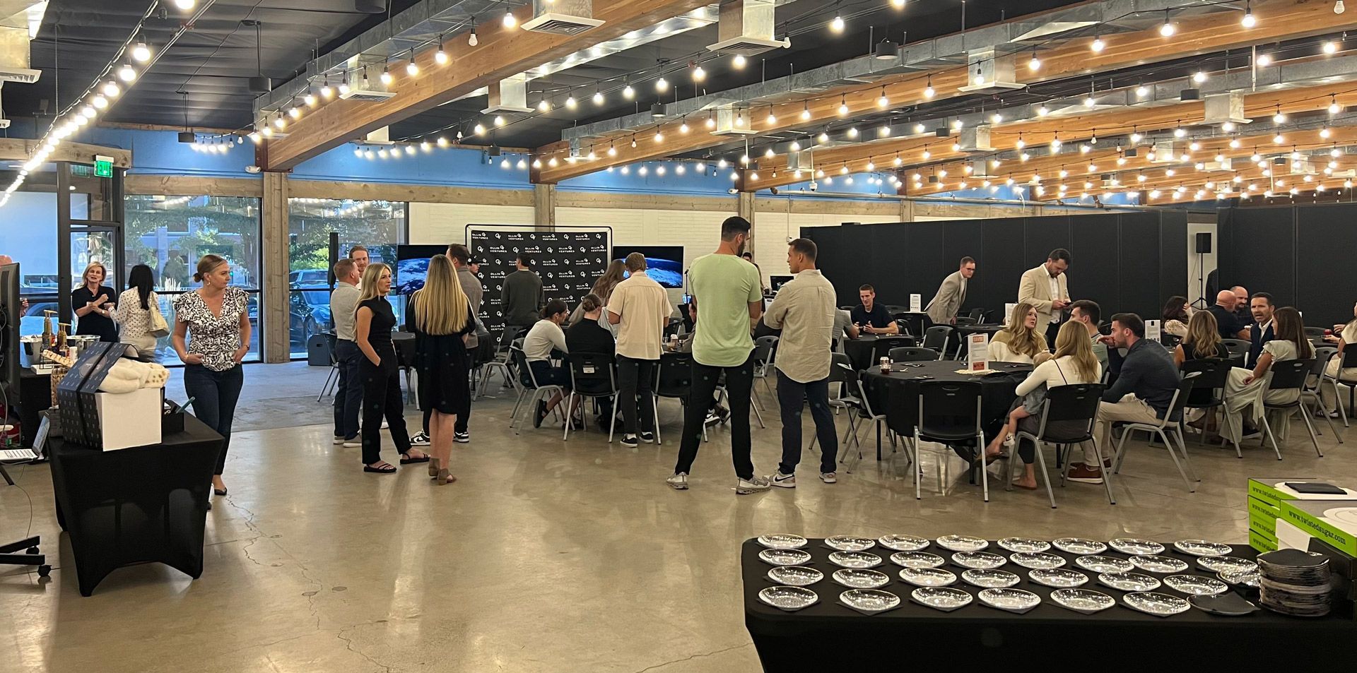 A group of people are standing around tables in a large room.