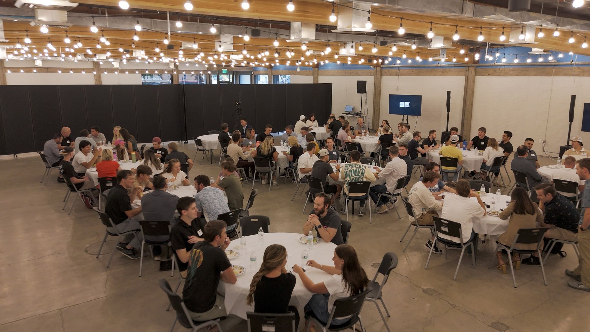 A large group of people are sitting at tables in a large room.