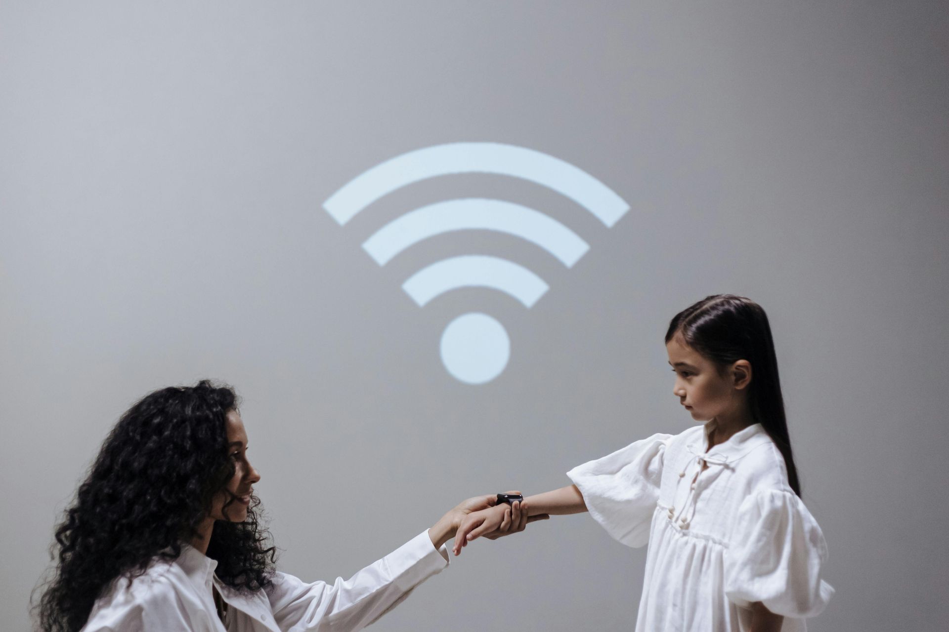 A woman and a little girl are shaking hands in front of a wifi symbol.