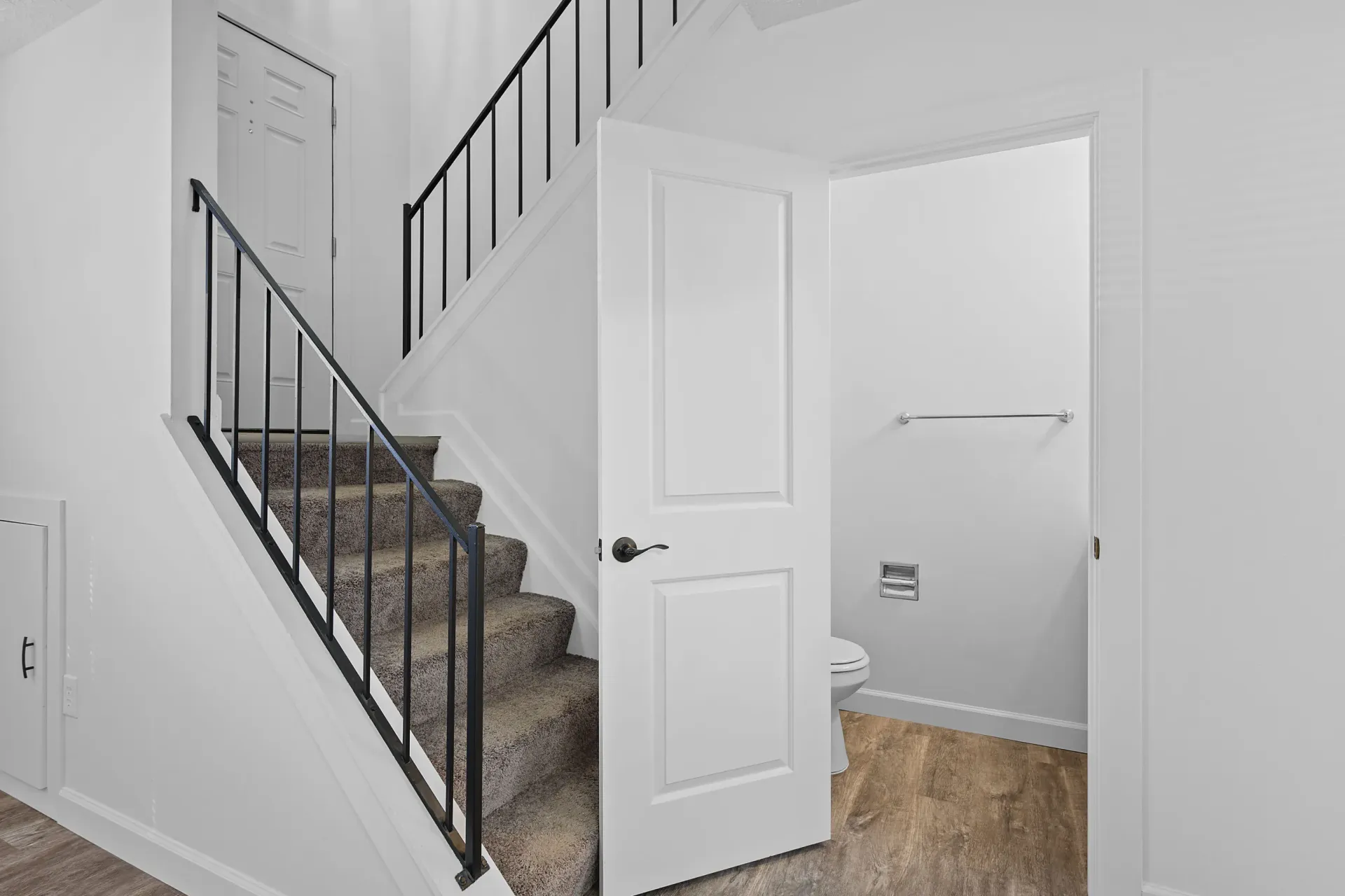 Interior stairwell with white walls and an open doorway to a small bathroom featuring a toilet.
