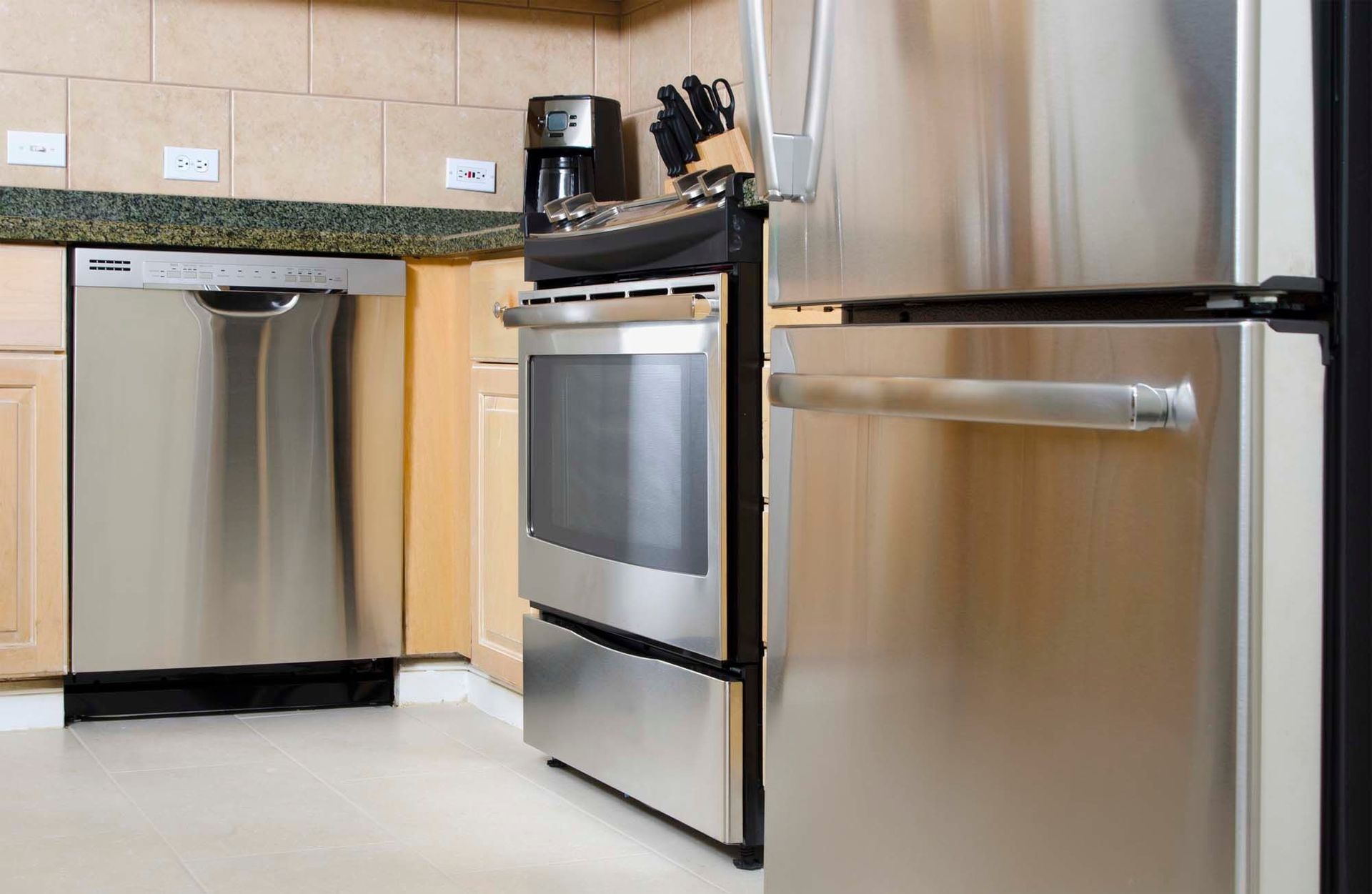 Stainless steel appliances (dishwasher, oven, and refrigerator) in a modern apartment kitchen.