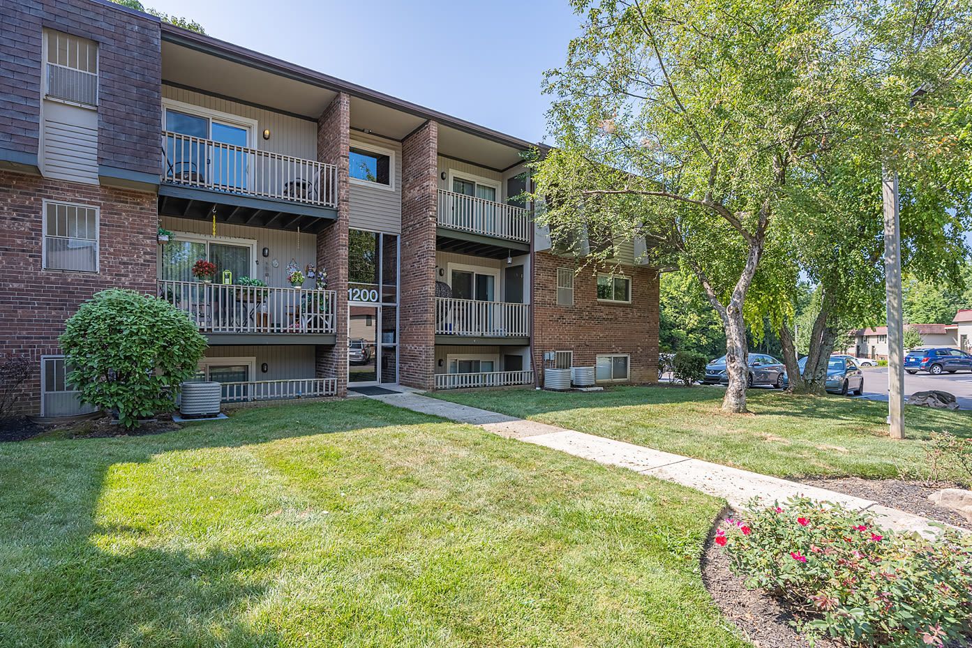 Exterior view of a brick apartment building with balconies and a grassy lawn.
