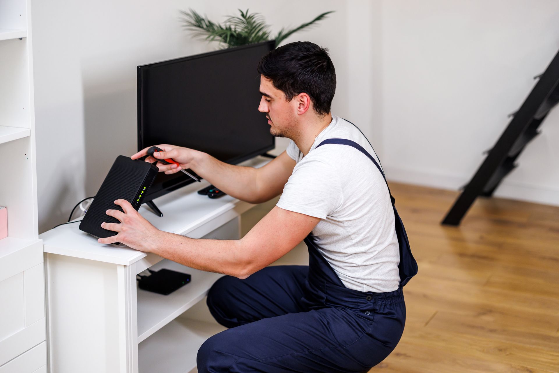 A man is working on a router in a living room.