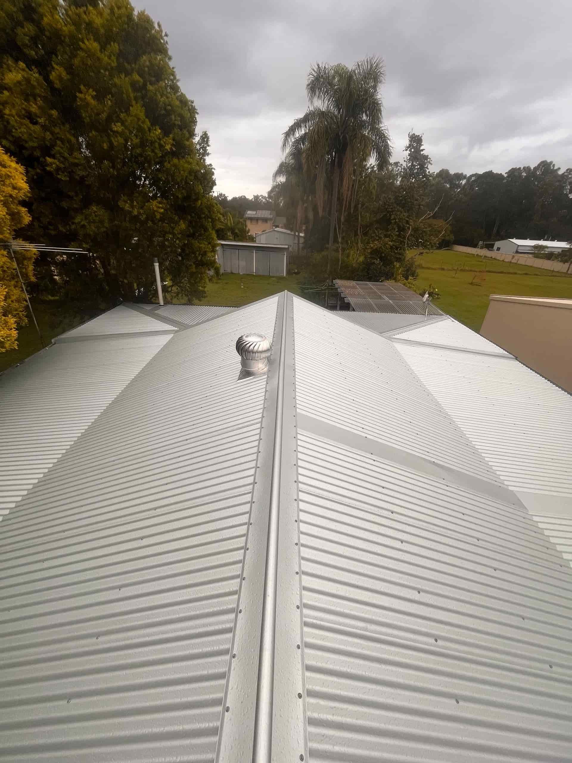 A Silver Corrugated Metal Roof With Trees in the Background — Eli Mcauley Constructions in Grafton, NSW