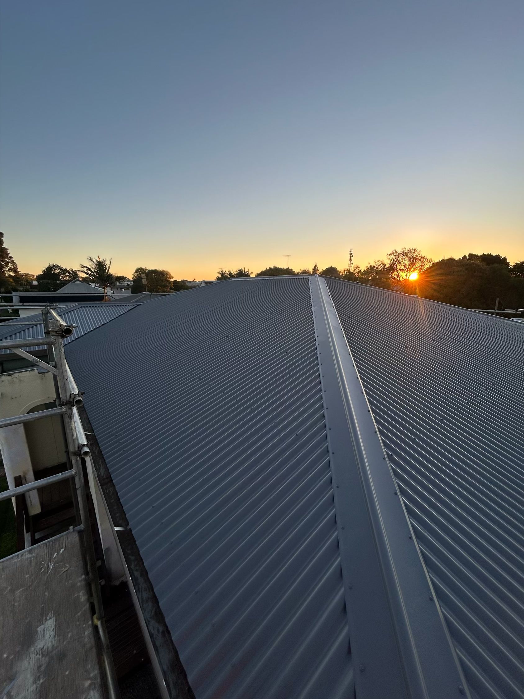Metal roof with ridges, sunset in background.