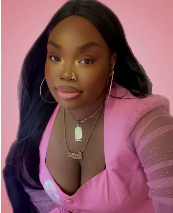 A woman wearing a pink top and a necklace with a name tag on it