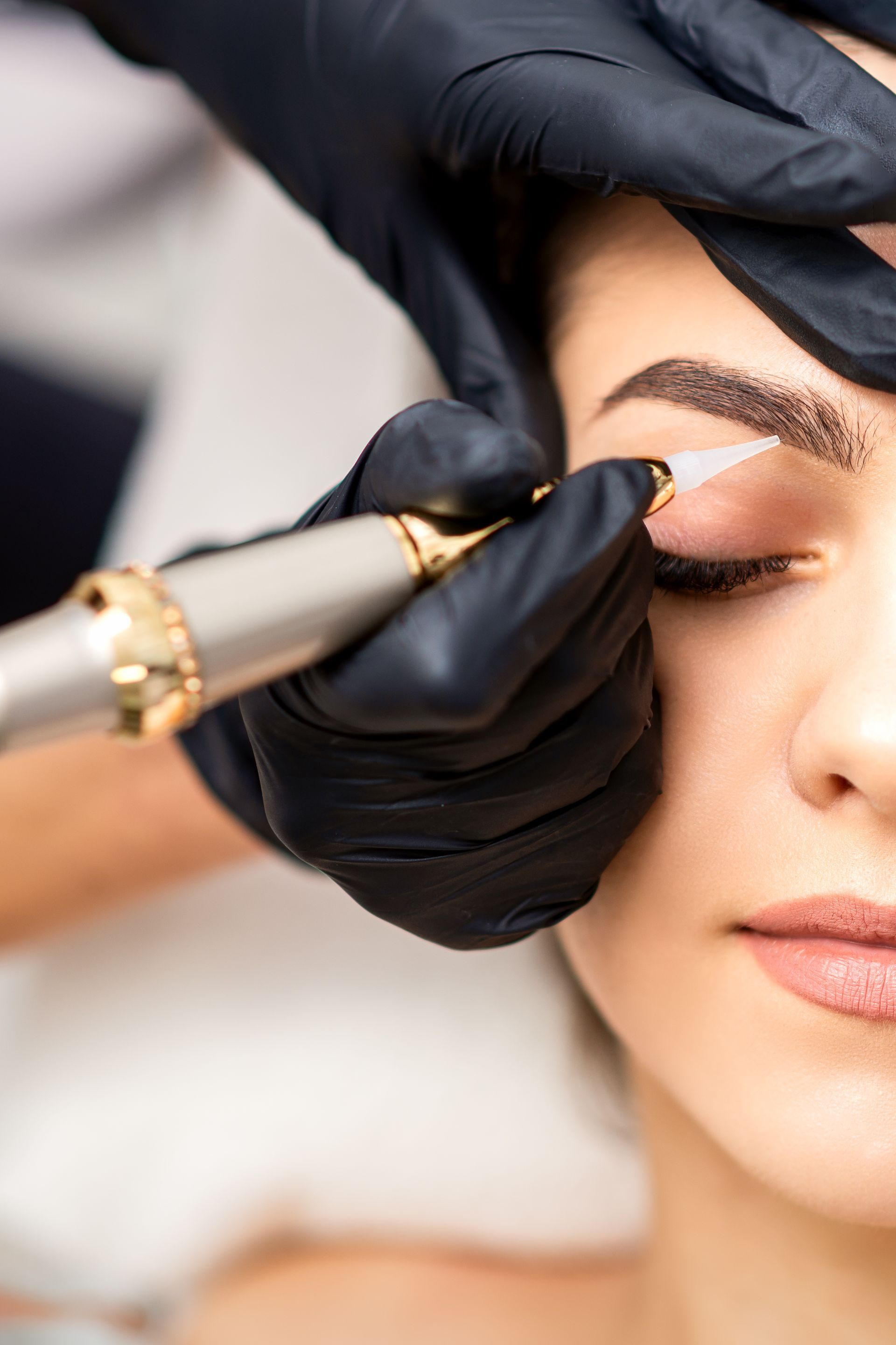 A woman is getting permanent makeup on her eyebrows.