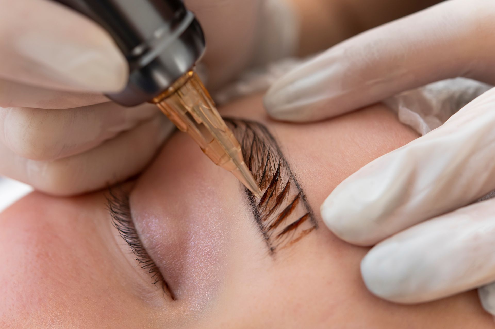 A woman is getting a permanent makeup tattoo on her eyebrows.