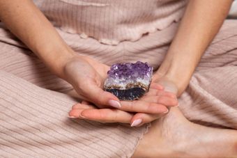 A woman is holding a piece of amethyst in her hands.