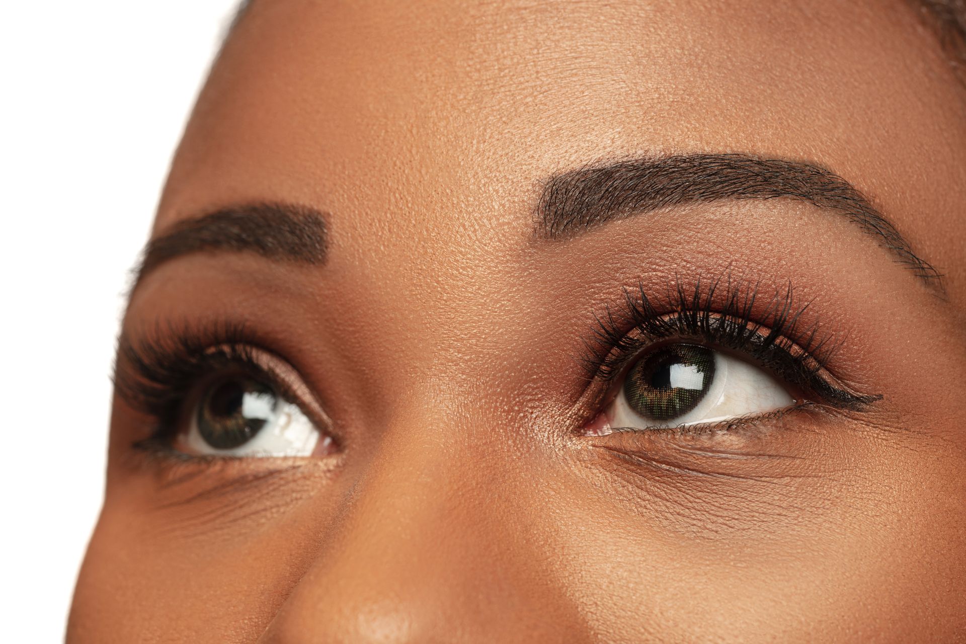 A close up of a woman 's nose and eye on a pink background.