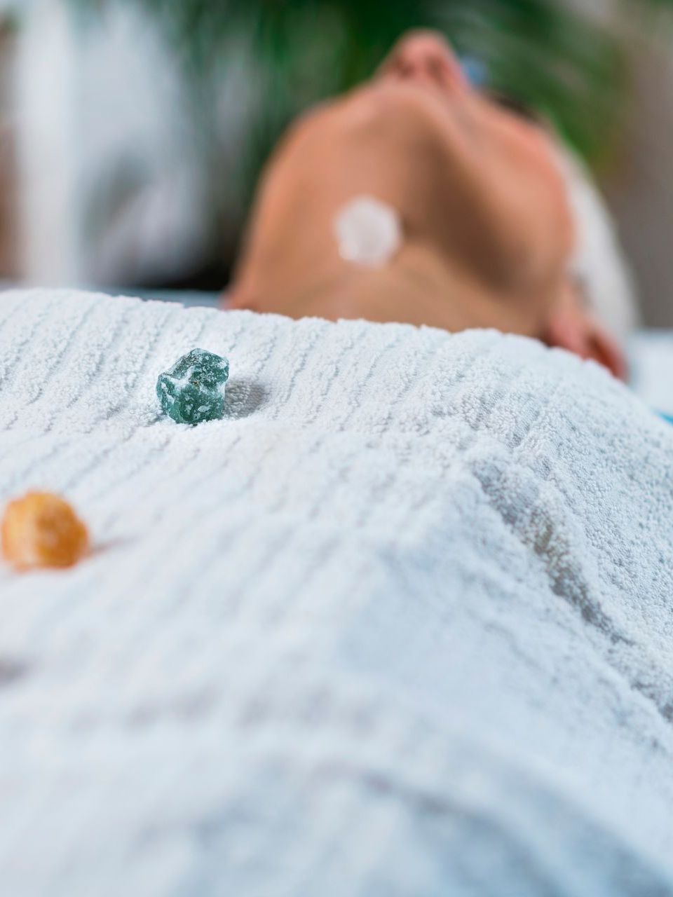 A person is laying on a bed with crystals on their body.