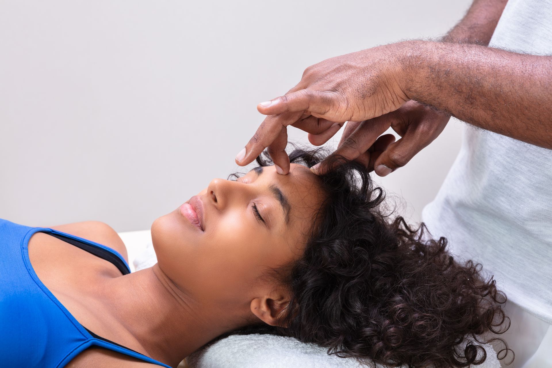 A woman is getting a head massage from a man.