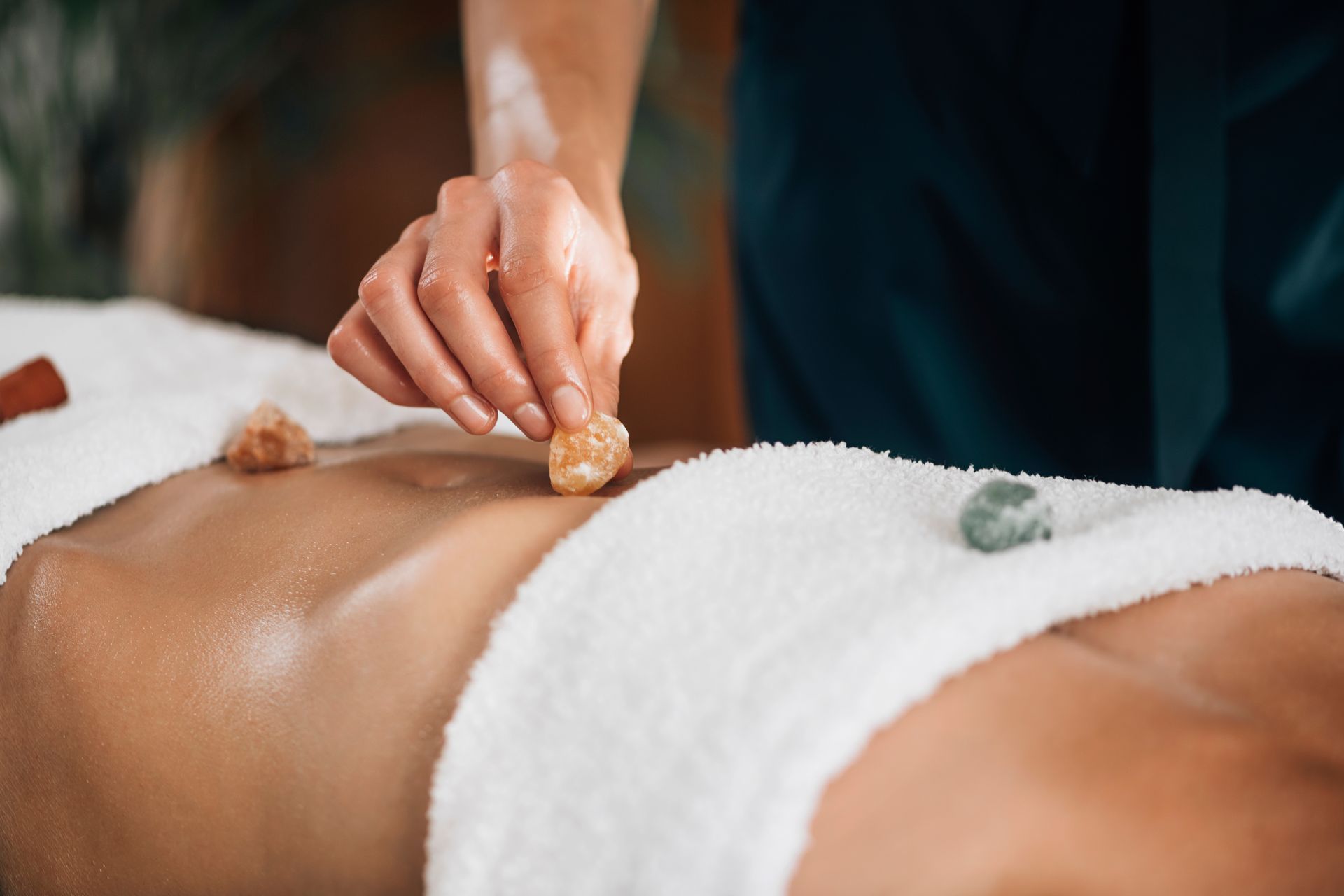 A woman is getting a massage with crystals on her back.