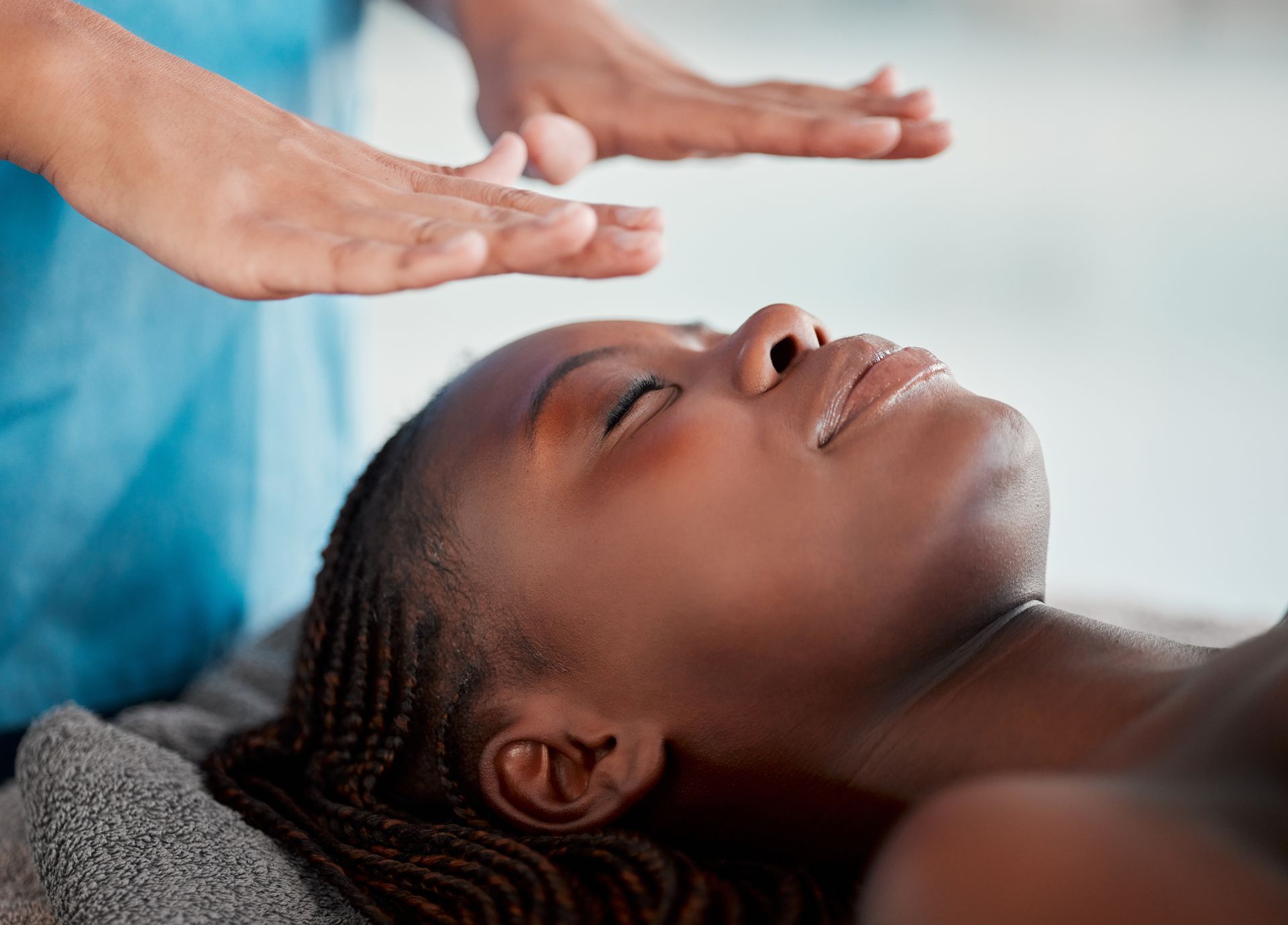 A woman is getting a healing massage with her eyes closed.