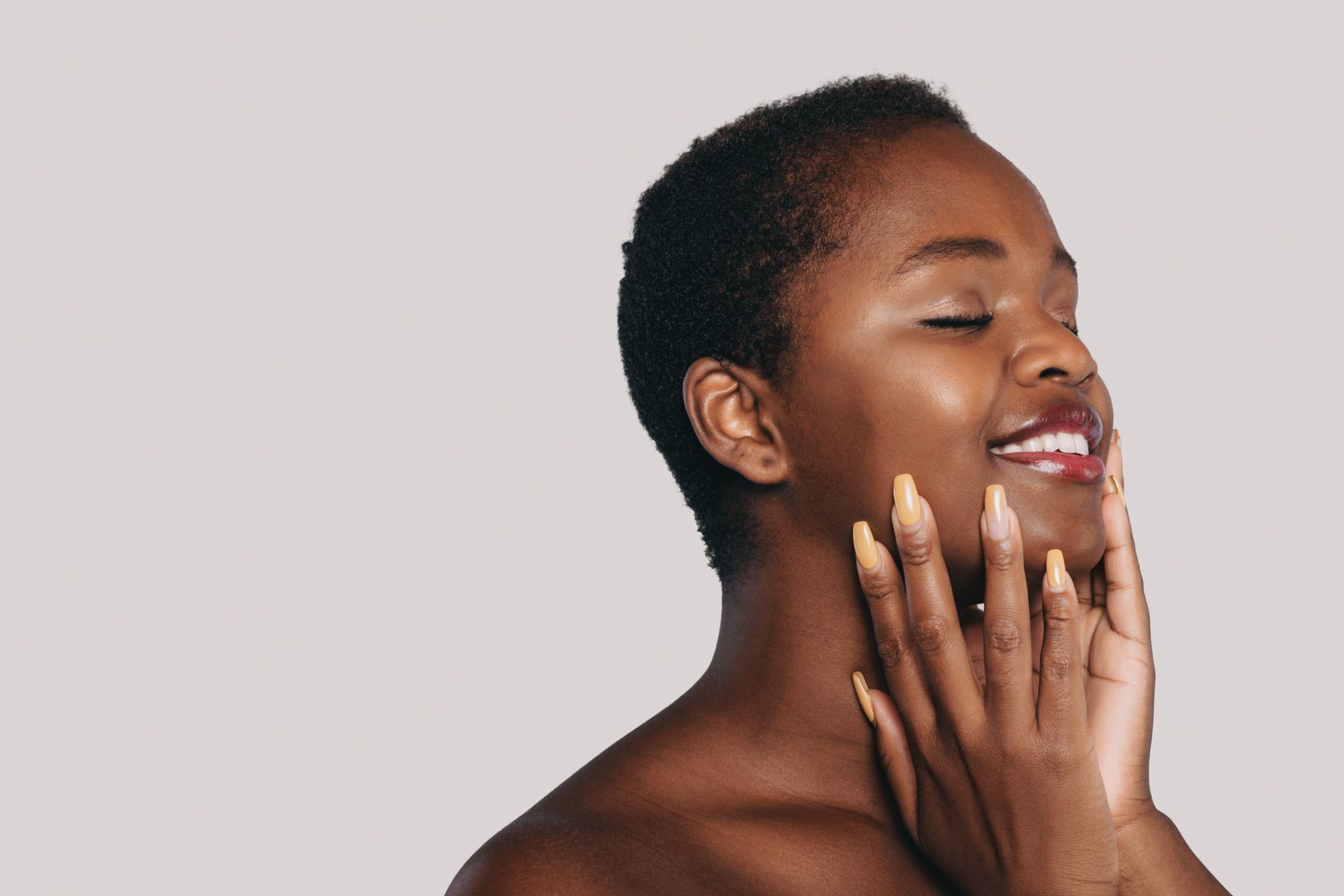 A woman is smiling with her hand on her face.