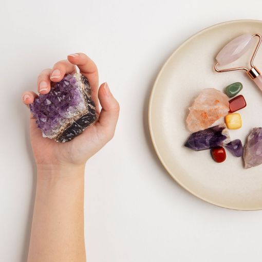 A hand holding a purple crystal next to a plate of crystals